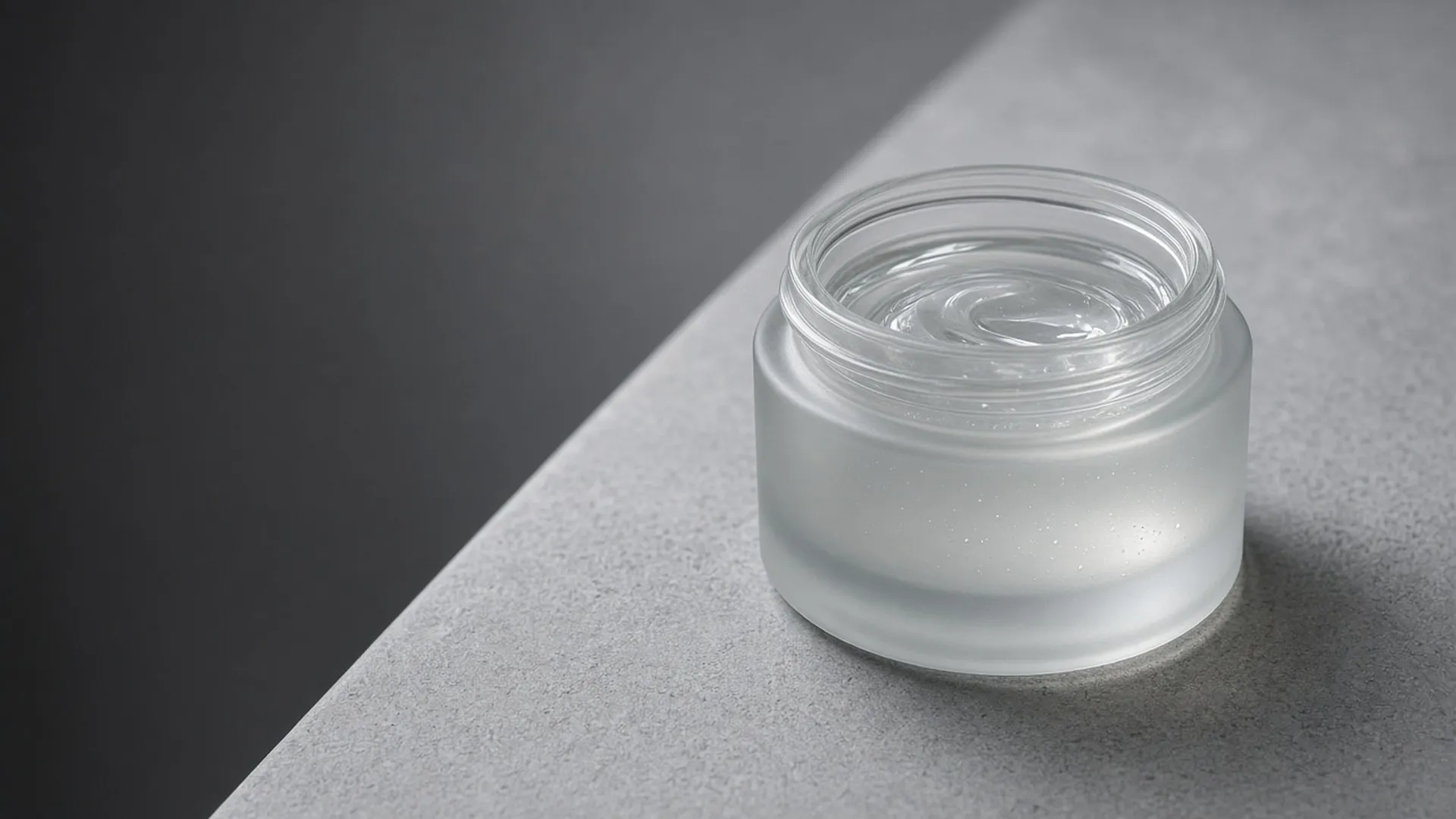 An open jar of clear gel on grey stone