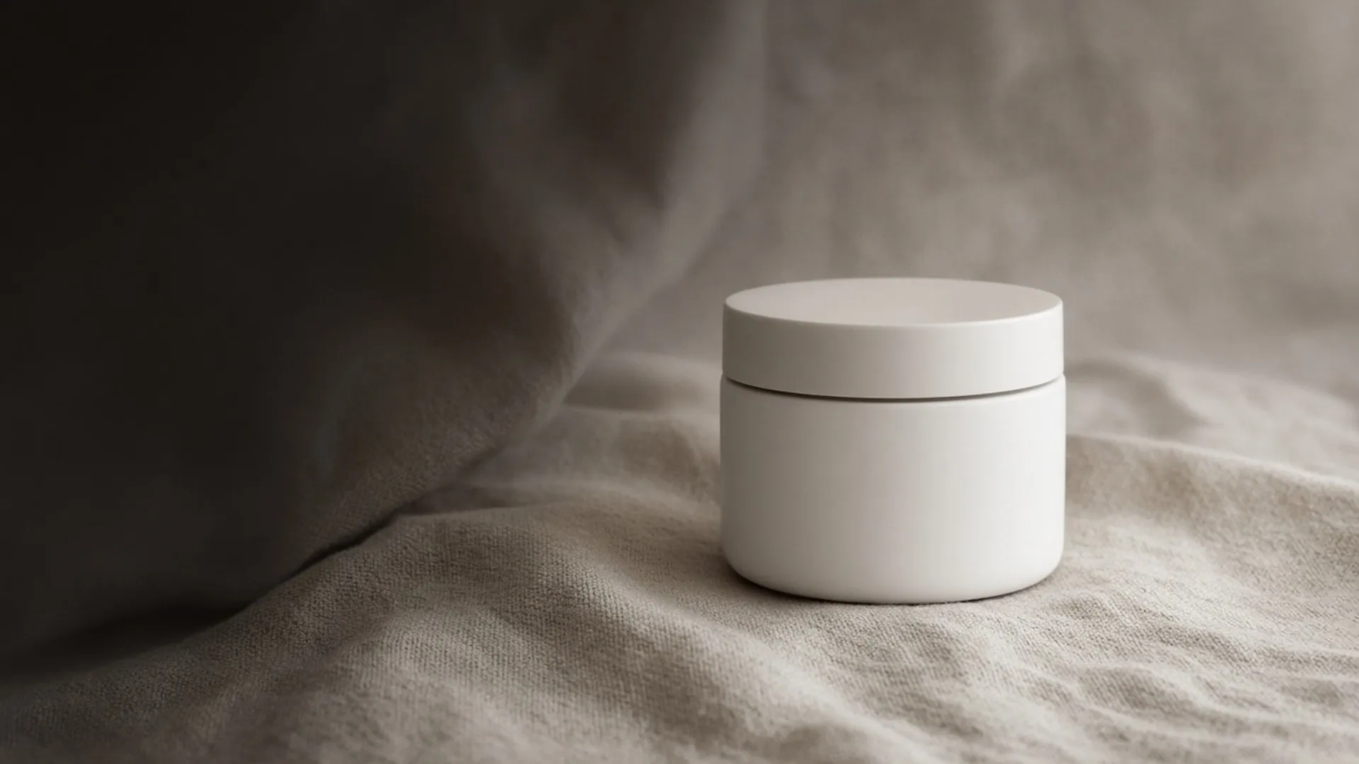 A single white jar on undyed linen