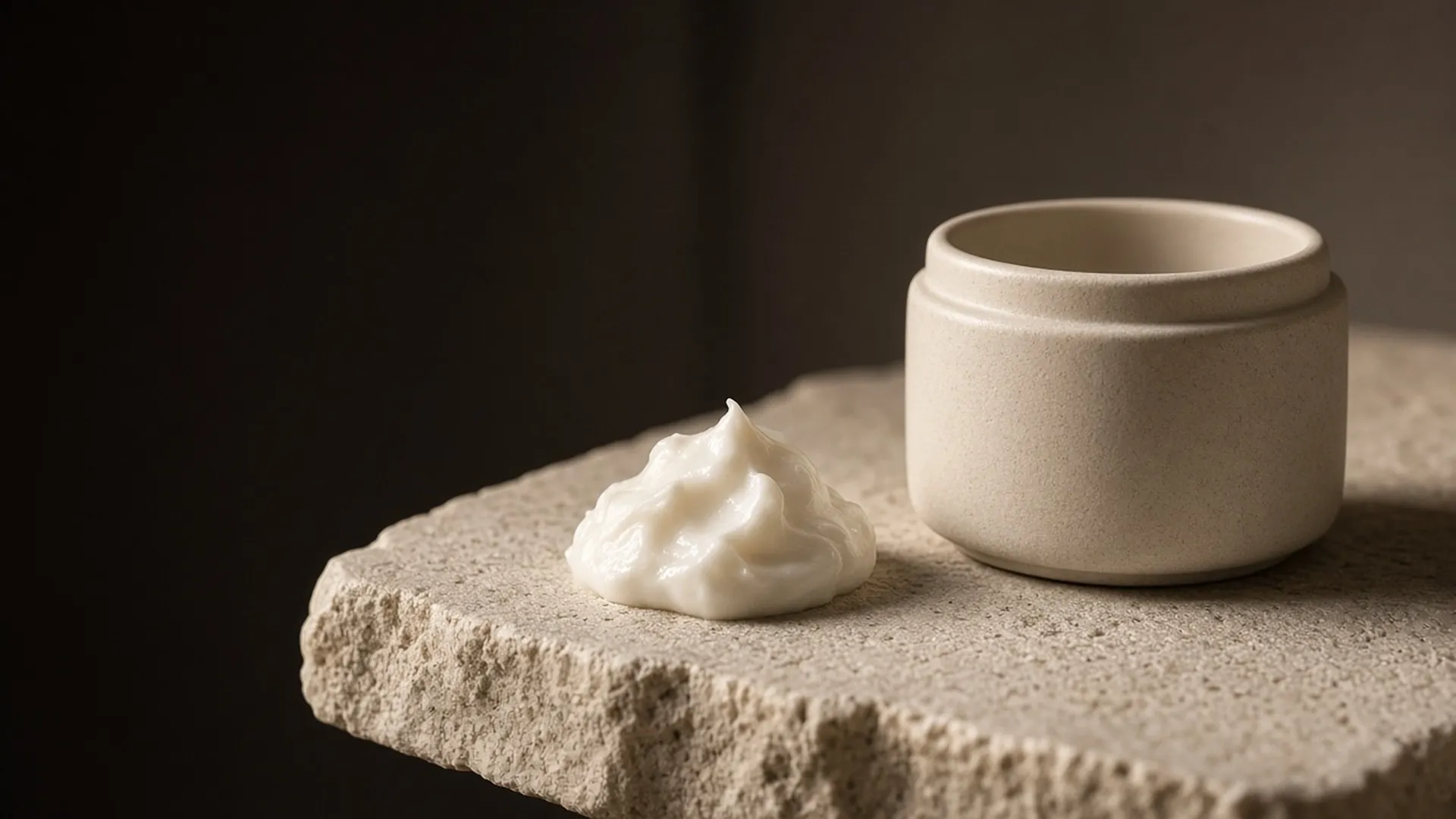 A dollop of ivory cream beside an open jar