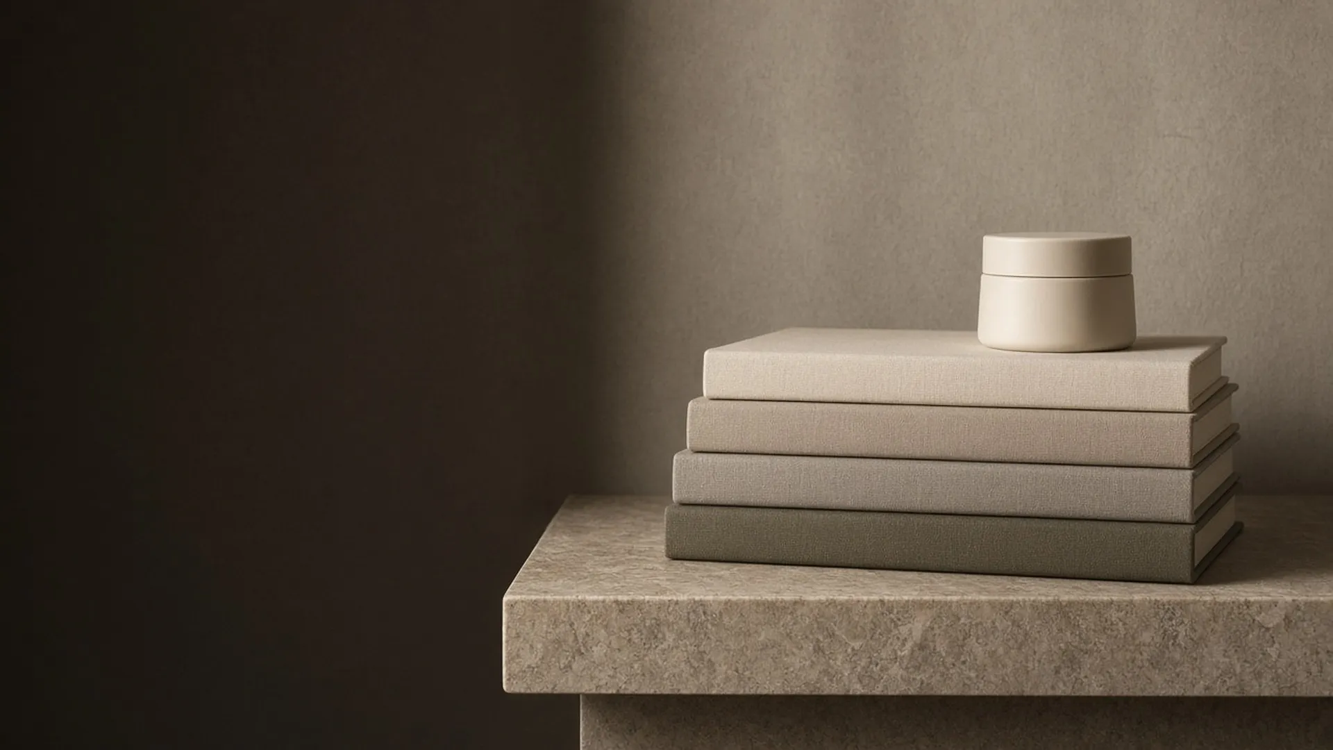 Plain books beside a jar on a stone shelf