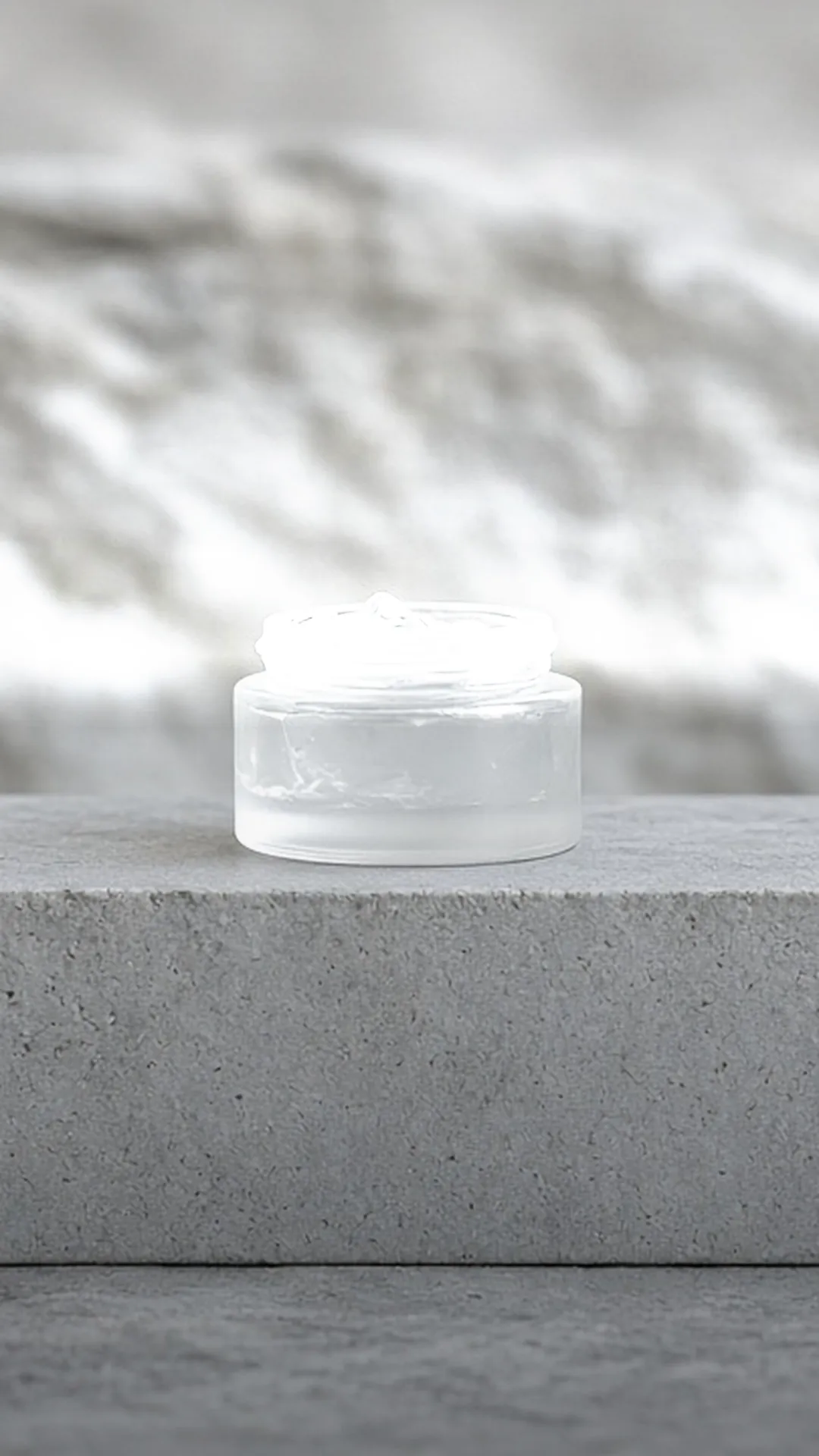 An open jar of clear gel on grey stone