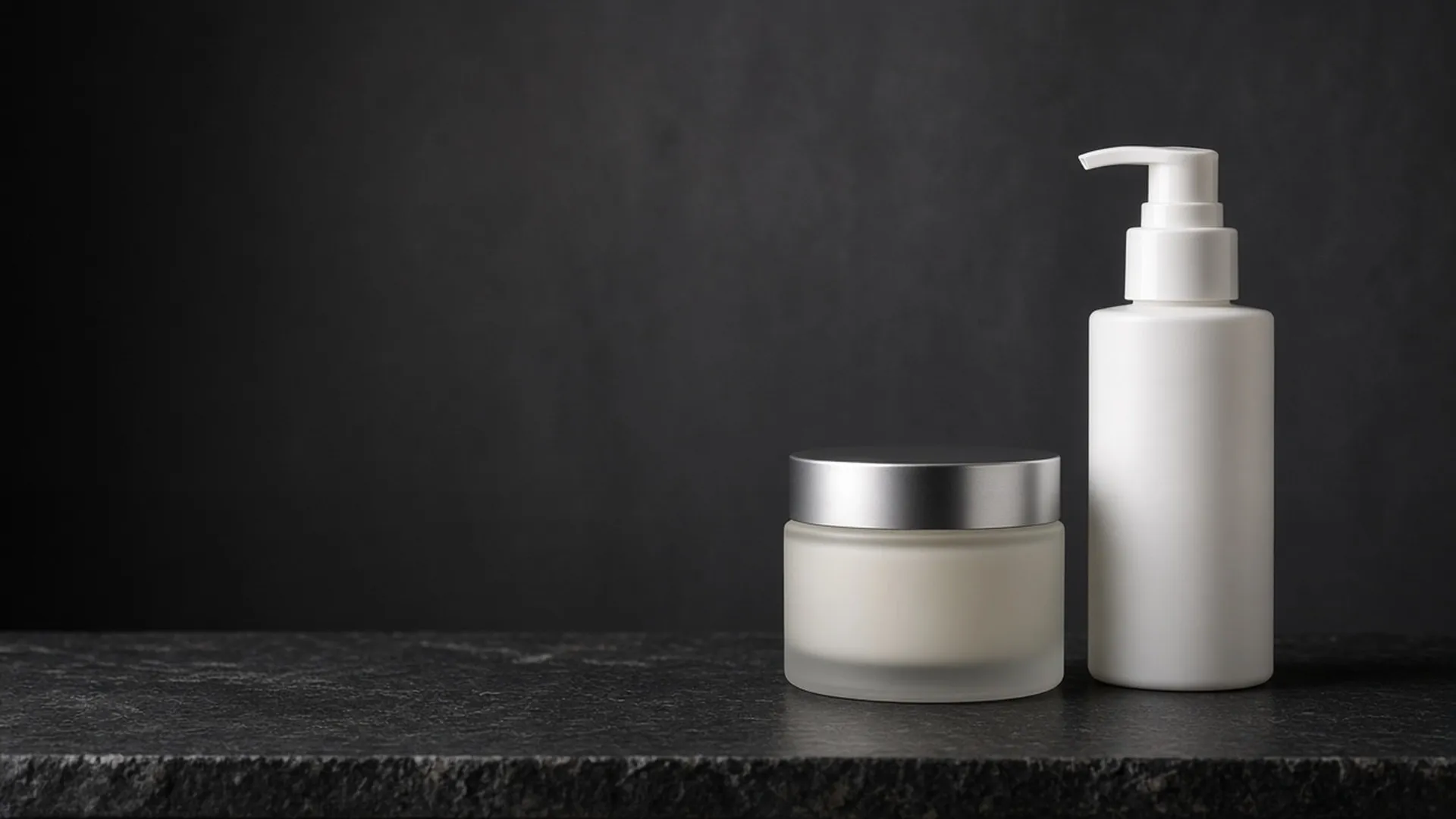 A frosted jar and a plain white bottle on a stone ledge